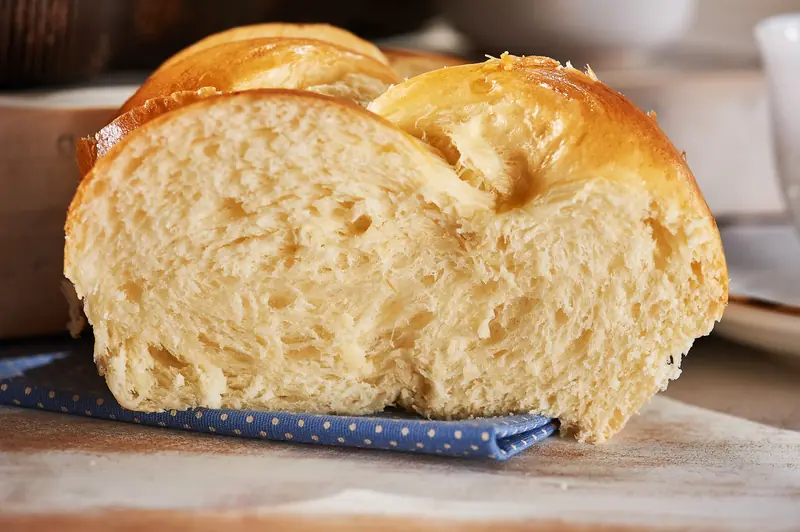 Miolo macio e fibroso de uma trança de brioche recém-partida, com a casca dourada e brilhante