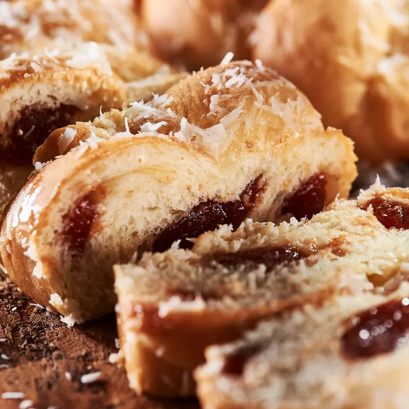Fatias de trança doce recheada de goiabada, polvilhada com coco ralado, em close