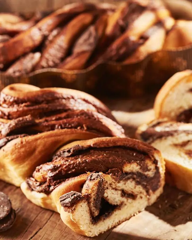 Trança doce recheada de chocolate cremoso, partida ao meio, mostrando as camadas de massa e recheio